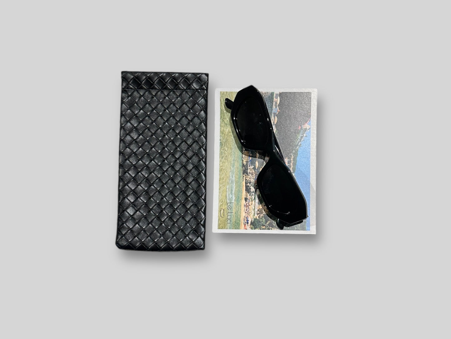 Sofia Polarised Acetate Sunglasses in Black displayed alongside a black textured case on a neutral background.