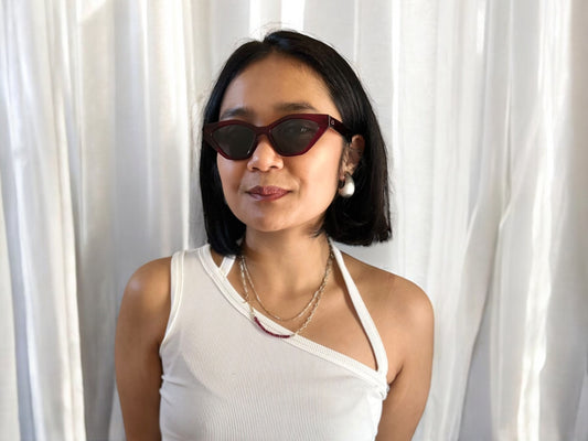 Model wearing Serena Cat Eye Polarised Acetate Sunglasses in Red with a white singlet, posing against a neutral background.